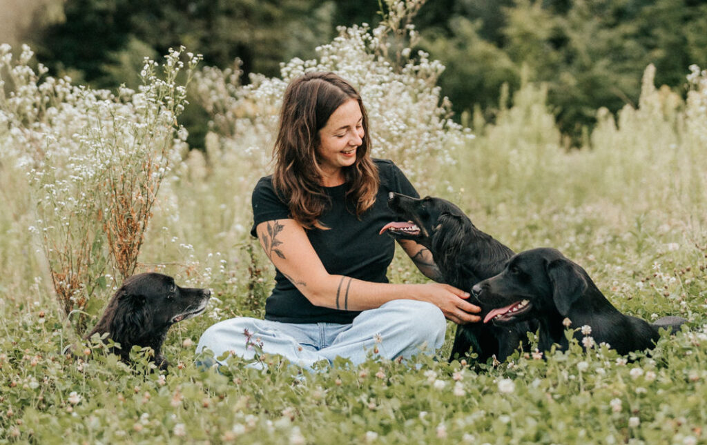 Hanna nowak mit drei schwarzen Hunden in der Wiese
