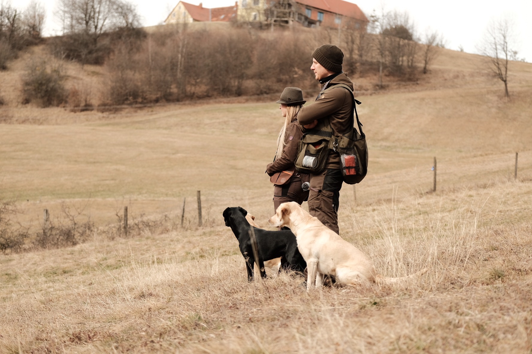 Zwei Hunde warten mit ihren Menschen beim Dummy-Training im Revier